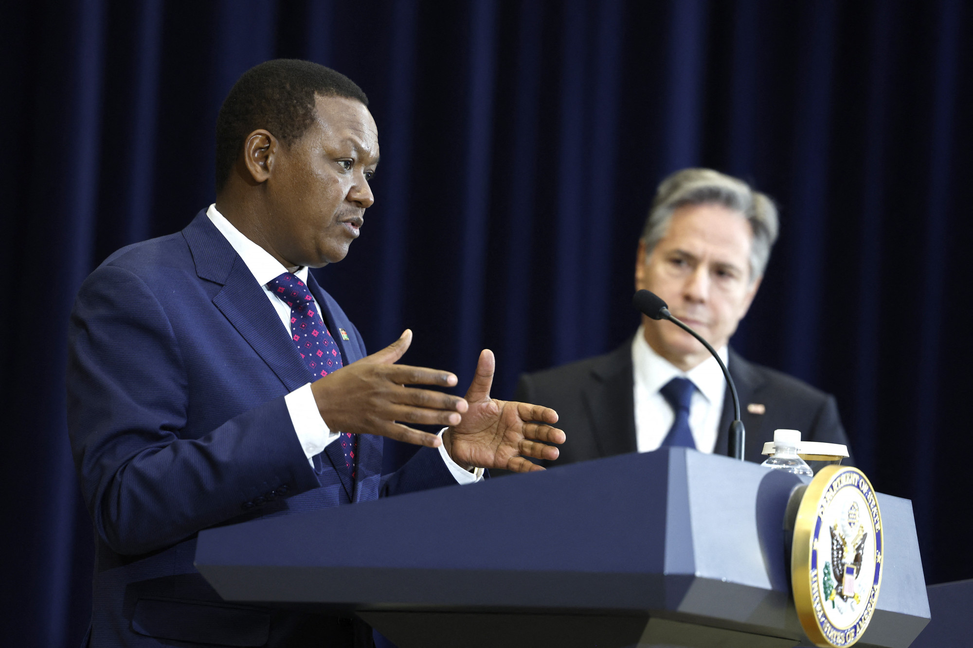 Alfred Mutua kenyai és Antony Blinken amerikai külügyminiszterek 2023. április 24-i egyeztetésük utáni közös sajtótájékoztatójukon Washingtonban. Egyeztetéseiken a szudáni polgárháború is téma volt, pár órával a tanácskozás után sikerült is fegyverszünetet közvetíteniük a polgárháborúzó felek között.