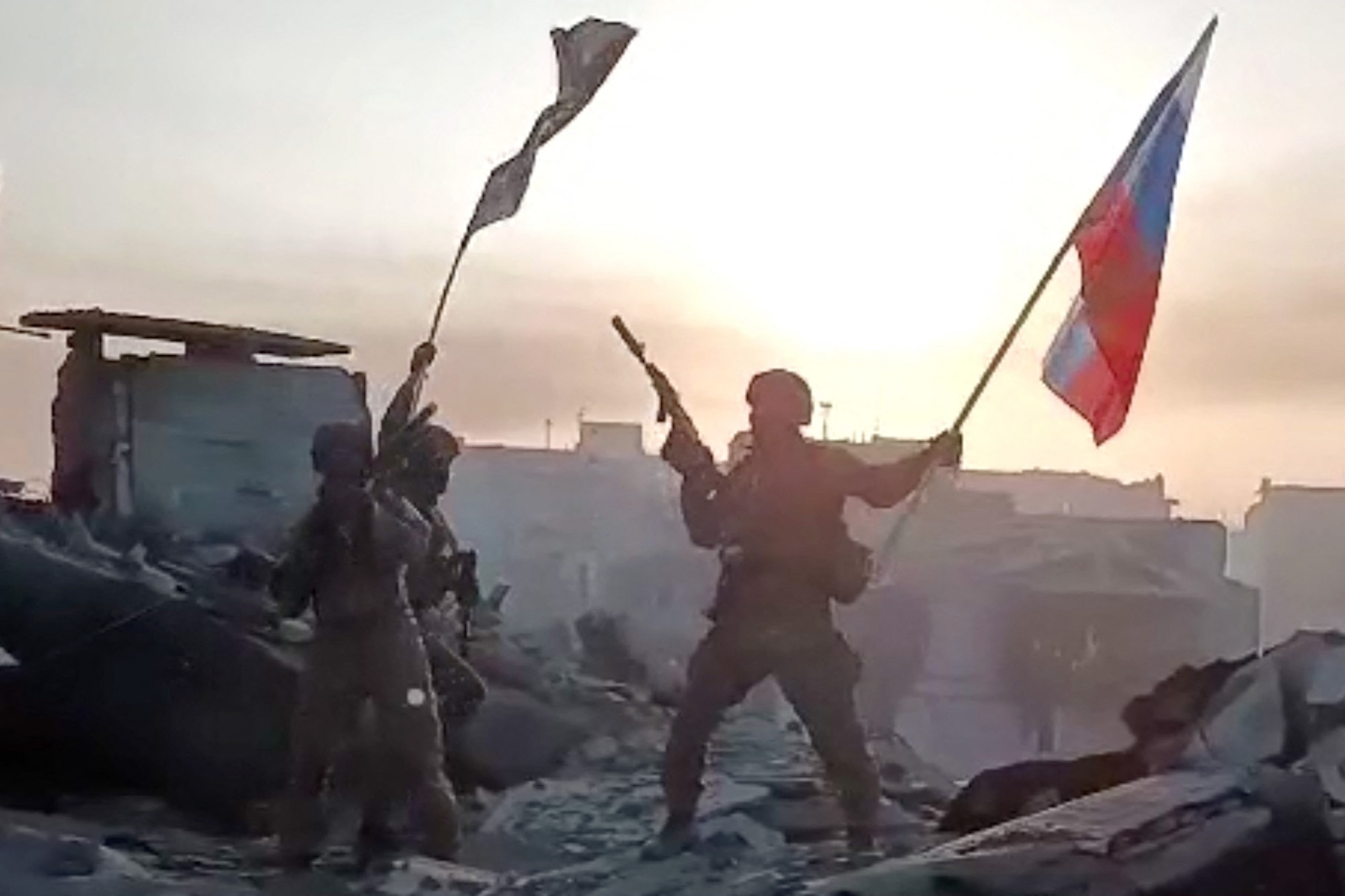 A wagner harcosai orosz zászlót lengetnek a porig rombolt Bahmutban 2023. május 20-án.