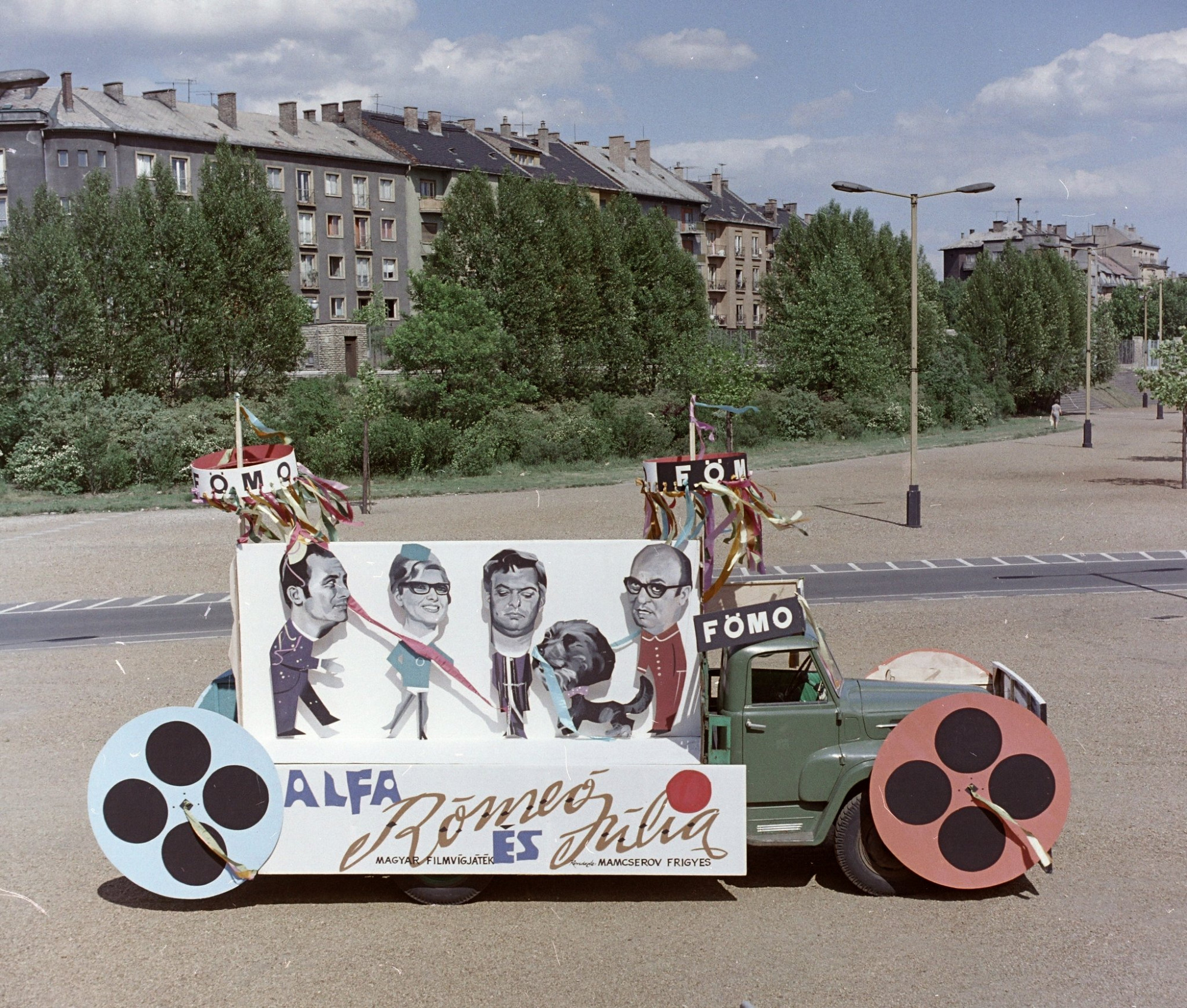 FőMo hirdetés egy Színészek–Újságírók Rangadó (SZÚR) alkalmával felvonuló teherautón a Népstadion melletti területen 1969-ben, háttérben a Stefánia (Népstadion) út házsora.