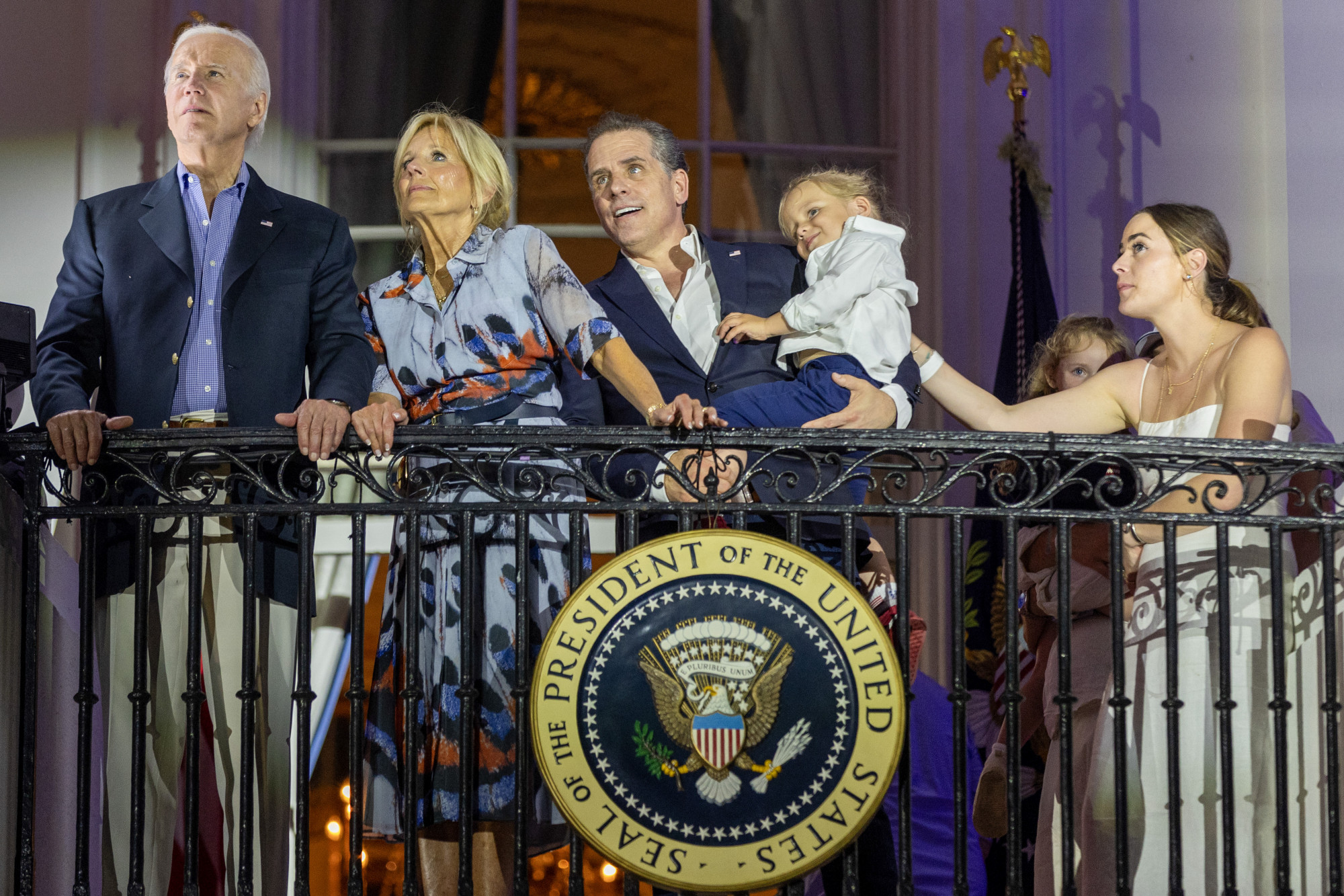 (B-J) Joe Biden és neje, Jill, a fia, Hunter, kezében unokaöccsével, Beau-val, és Naomi Biden, Hunter legnagyobb lánya 2023. július 4-én a Fehér Ház erkélyéről nézik az ünnepi tűzijátékot.