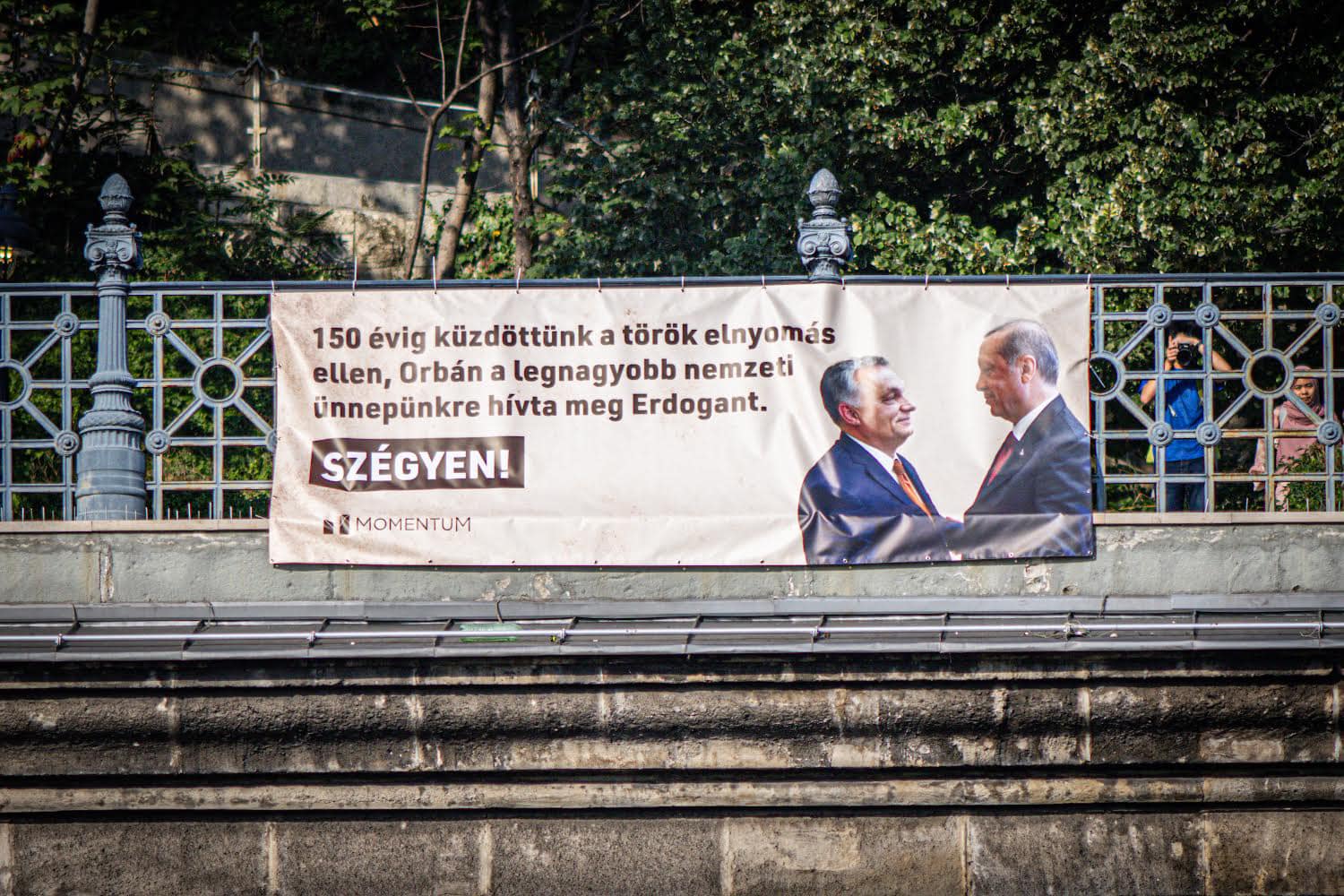 „Szégyen” feliratú molinóval köszöntötte a Momentum az államalapítás ünnepén díszvendégként Orbán Viktorhoz látogató Erdogant