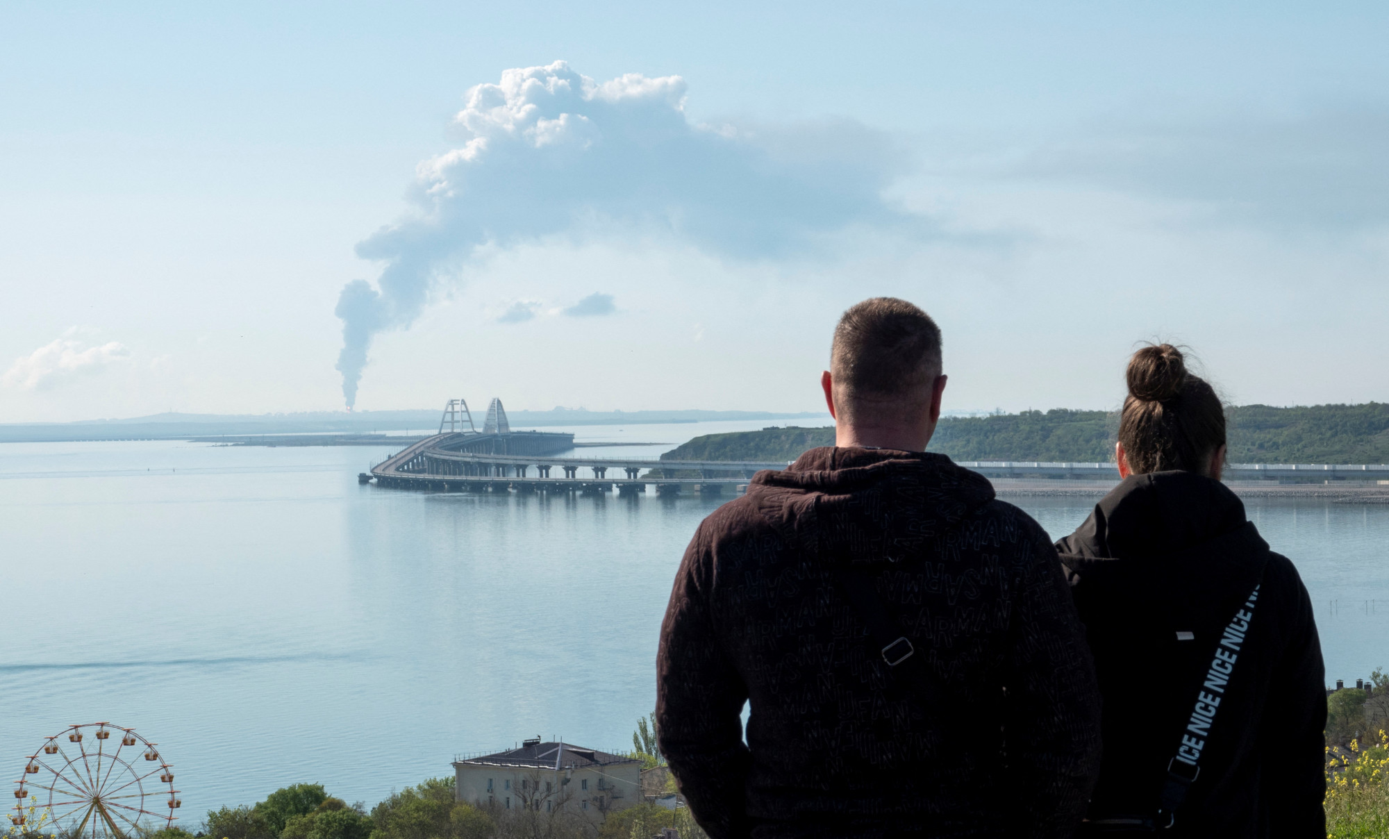 A kercsi híd a háttérben egy füstölgő üzemanyagtározóval.