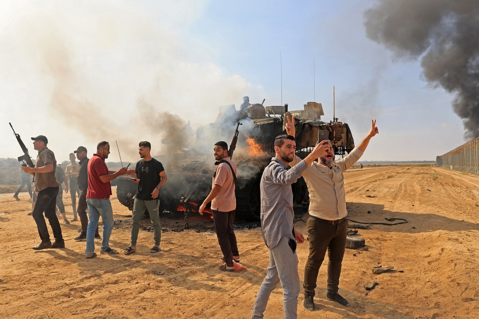 Palesztinok átveszik az irányítást egy izraeli tank felett, miután átlépték az izraeli határkerítést a Gázai övezet déli részén fekvő Hán Júnisznál 2023. október 7-én .