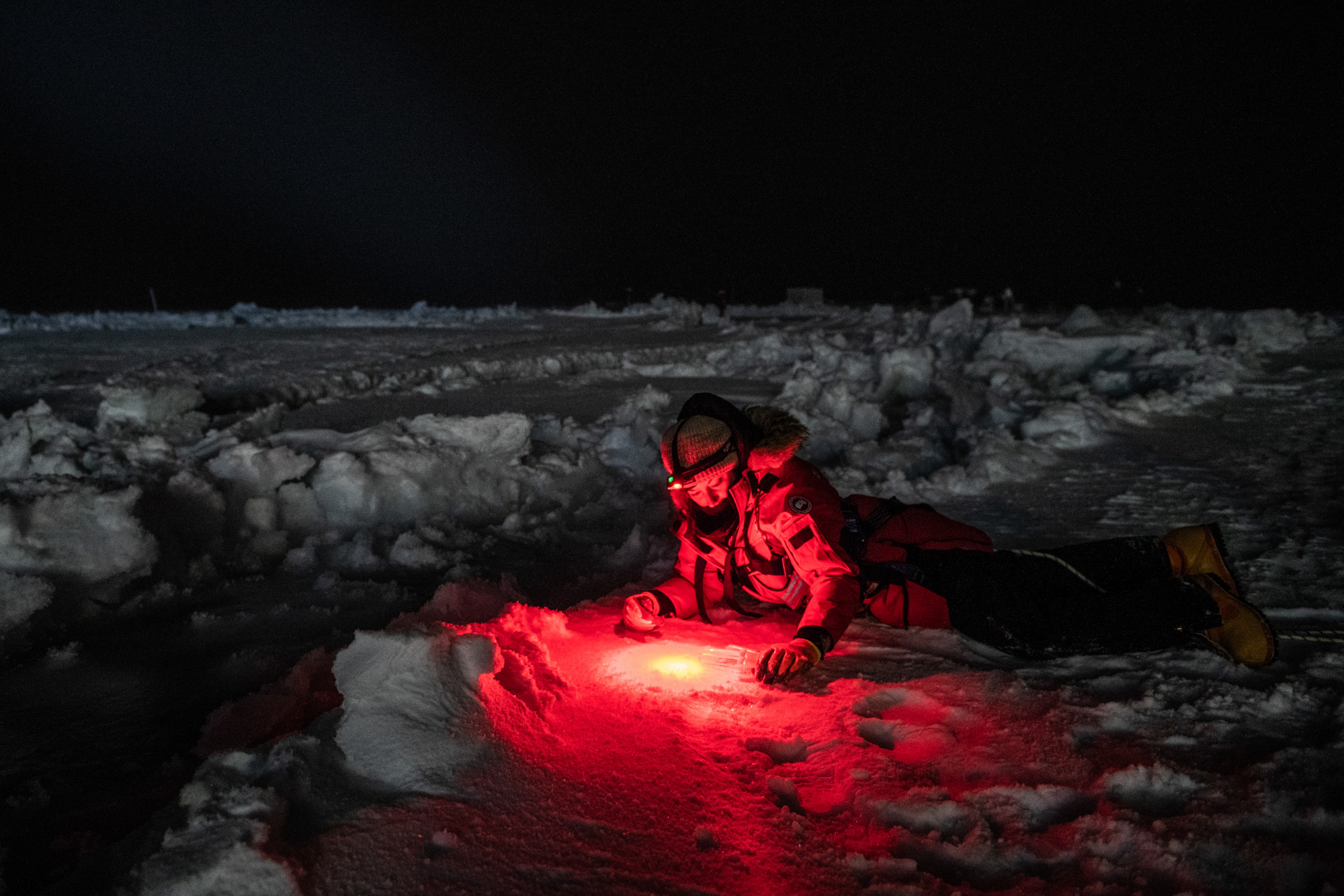Jessie Creamean egy jéglék mellett fekszik, hogy vízmintát gyűjtsön a Jeges-tengerből.