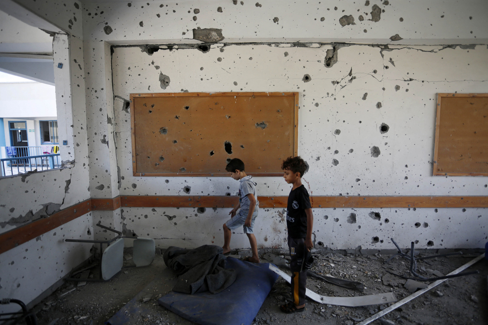 Fiatal fiúk állnak egy repeszekkel teli szobában egy ENSZ által működtetett iskolában a Gázai övezet középső részén található Al-Maghazi menekülttáborban, egy nappal azután, hogy legalább 6 ember meghalt egy izraeli támadásban, 2023. október 18-án. Több tucat ember, köztük az UNRWA munkatársai is megsebesültek, és az iskola súlyos szerkezeti károkat szenvedett - közölte az ENSZ palesztin menekülteket segítő szervezete.