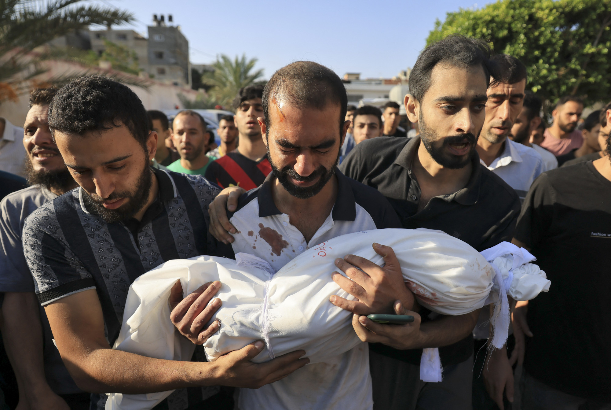 A házukat ért izraeli légicsapás során megölt al-Majaida család egyik gyermekének apja viszi a holttestet a temetésen a Gázai övezet déli részén fekvő Khan Yunisban 2023. október 19-én.