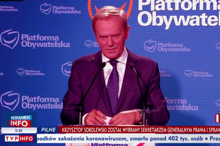 Tusk-Lucifer ördögszarvnak látszó háttérrel a TVP adásában