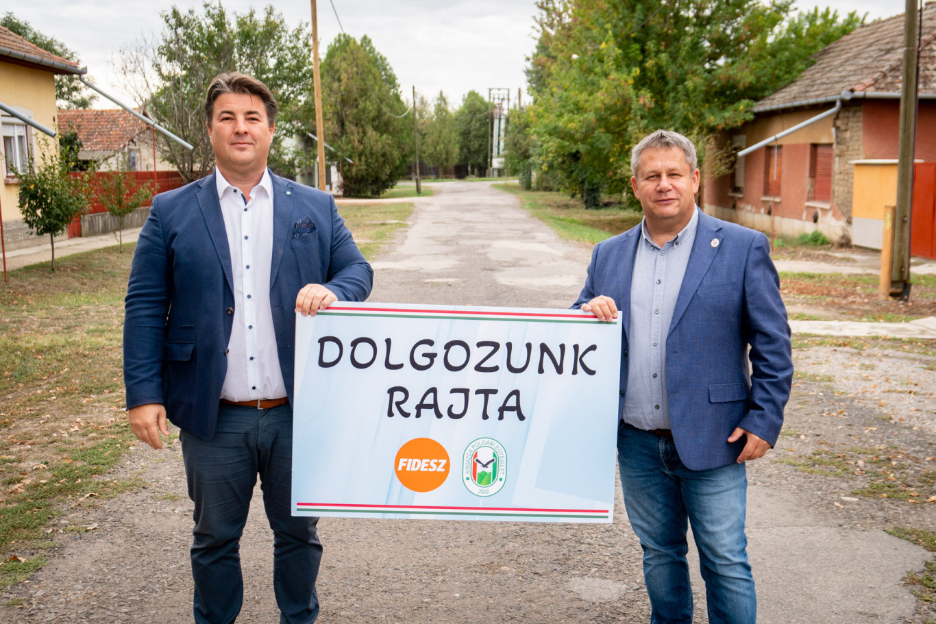 A kampány eddigi legjobb képe: „dolgozunk rajta” feliratú táblával pózolnak a fideszesek egy kátyús utcán