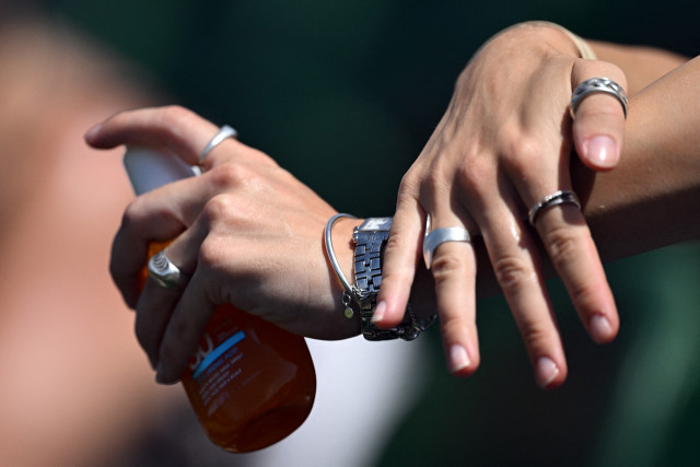 A woman applies sunscreen on her hands, on the fifth day of the 2026 Wimbledon Championships at The All England Lawn Tennis and Croquet Club in Wimbledon, southwest London, on July 3, 2026. (Photo by Kirill KUDRYAVTSEV / AFP) / RESTRICTED TO EDITORIAL USE